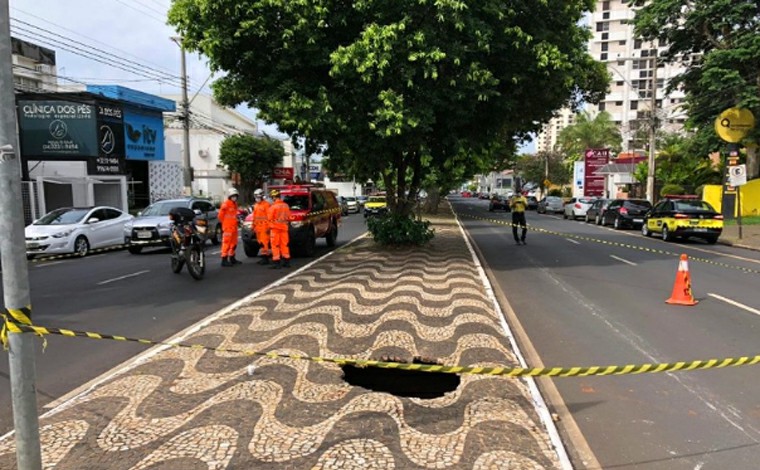 Calçada de canteiro central cede e jovem cai dentro de cratera em avenida de Uberlândia